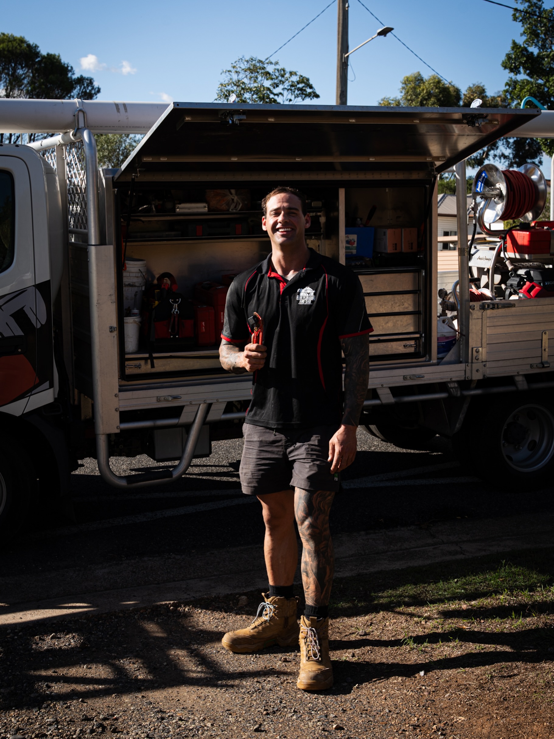A Hovi Plumbing and Gas tradesman with a pipe wrench in front of the fully stocked service truck