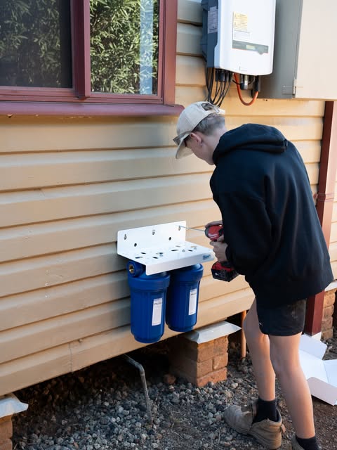 A Hovi Plumbing apprentice mounting a twin water filter housing at a Muswellbrook home